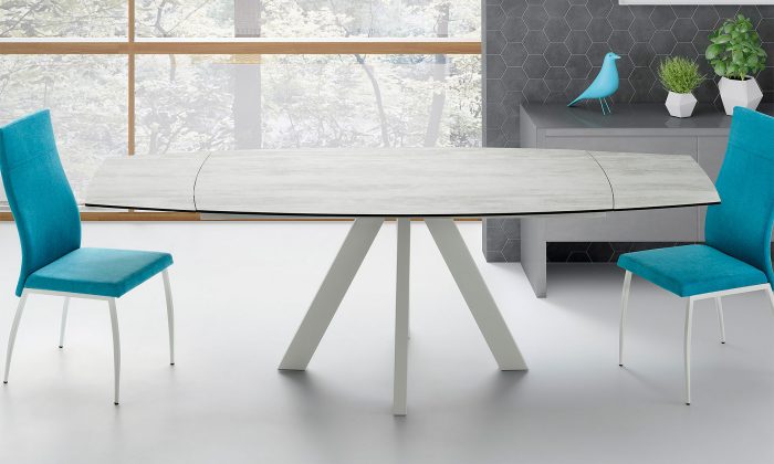 Photo d'ambiance présentant une salle à manger avec une table et deux chaises. La table à une finition blanc laqué pour les pieds et un plateau céramique avec allonges.